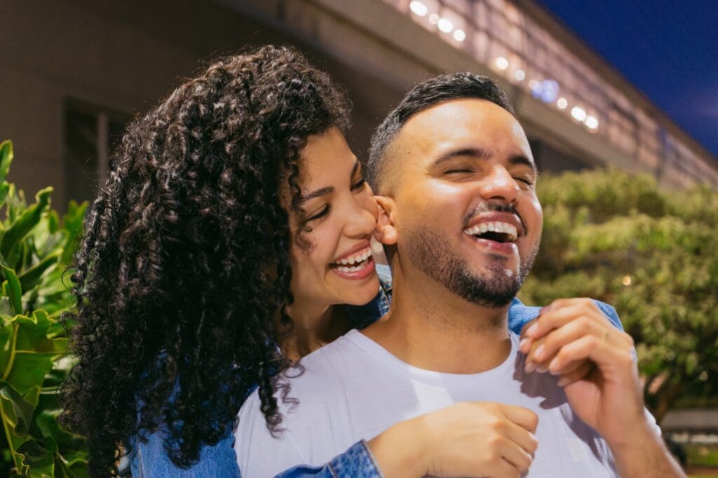 Latin couple smiling, hugging outside on a night date